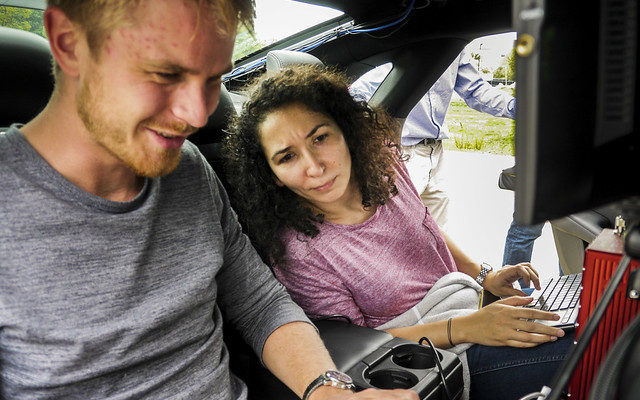 People in a car looking at a screen of a laptop